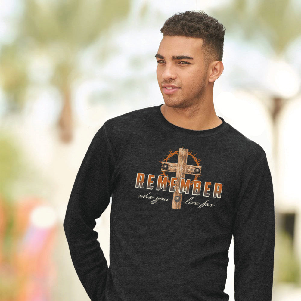 Man wearing a gray ong-sleeve shirt with a cross and text design outdoors.